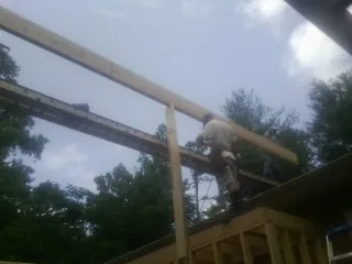 Carpenter setting a ridge beam over a new addition frame — Ice Dam Removal by Roofing Brothers in Weslaco