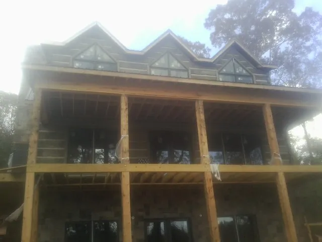 Dormers and porch framing on a large log home under construction — Roof Coating work by our crew in Weslaco