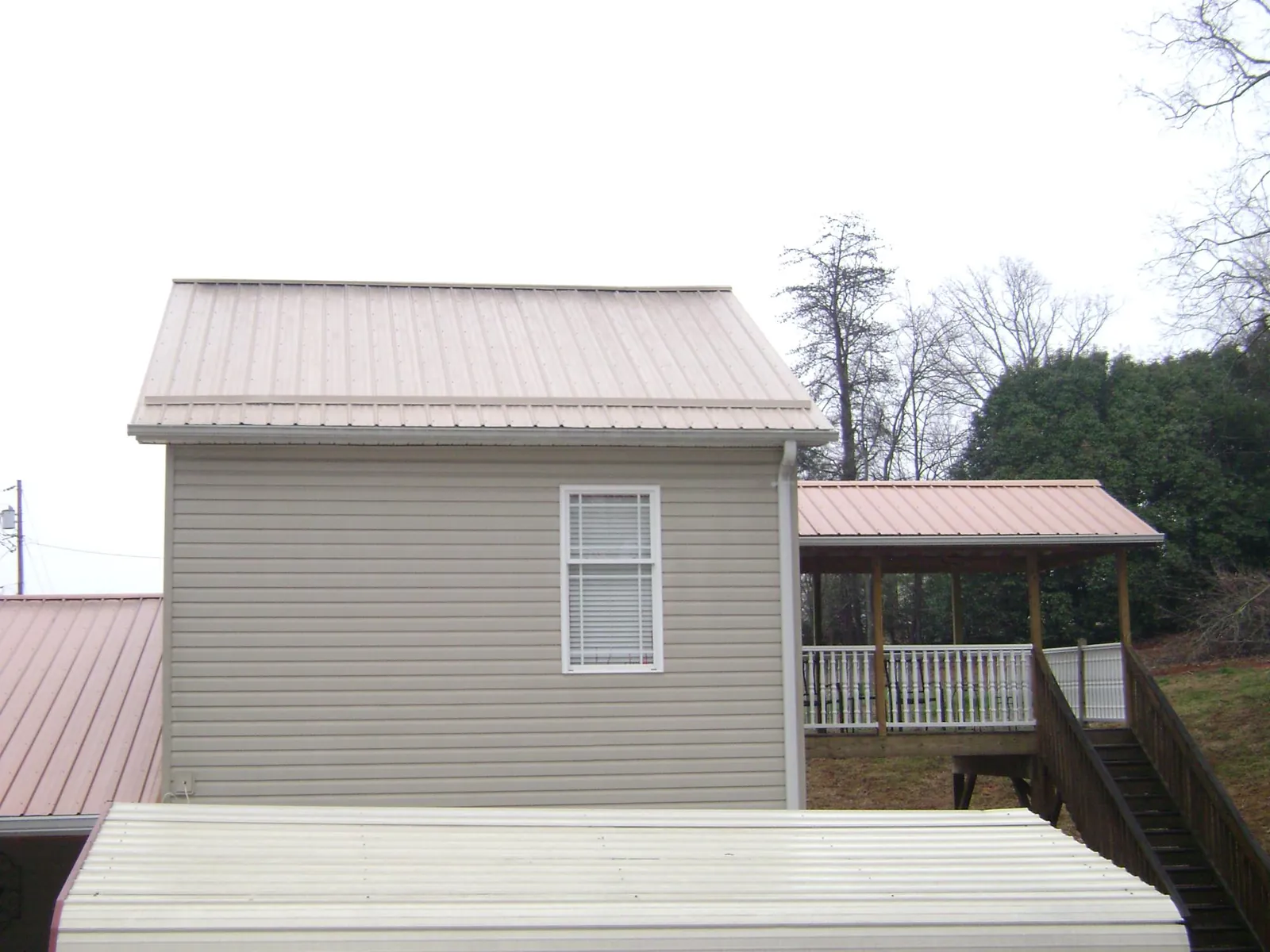 Tan metal roofs on a two story addition and attached porch, from a Roof Replacement job in Weslaco
