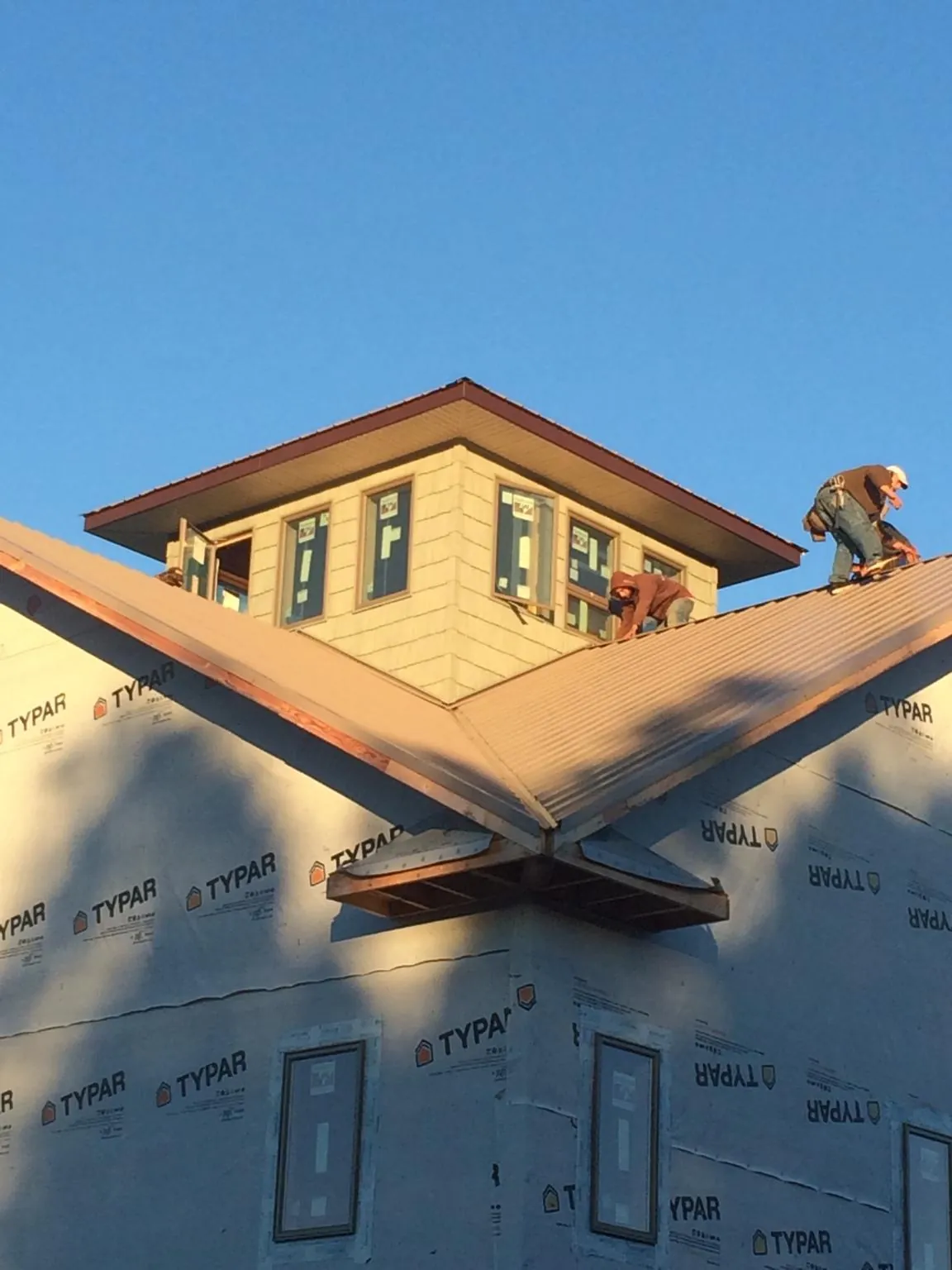 Roofers working around a rooftop cupola on a new metal roof at sunset — Roof Waterproofing in Weslaco by Roofing Brothers